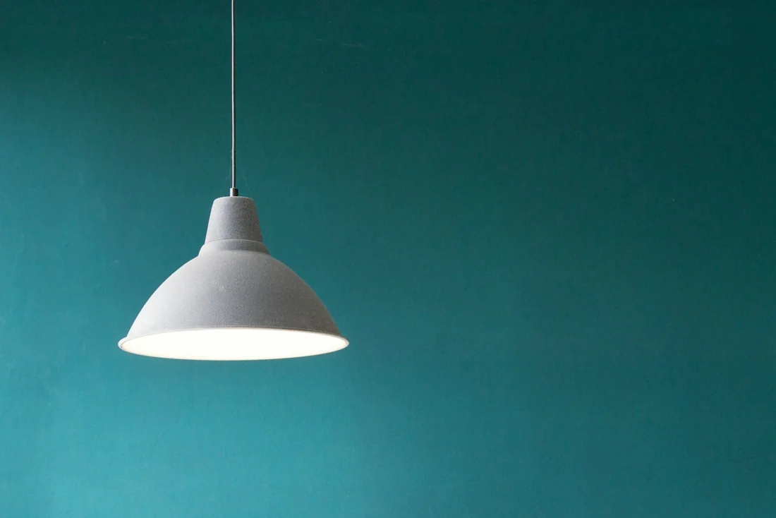 A single sculptural pendant light against a deep green wall